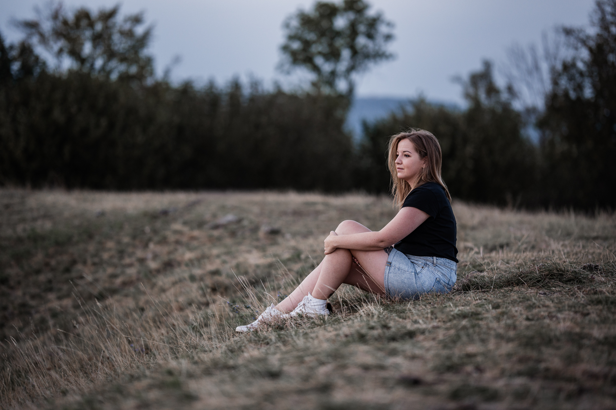 Hochzeitsfotografin Kristina Reinartz sitzt auf dem Boden am Walberla, Ehrenbürg in Franken