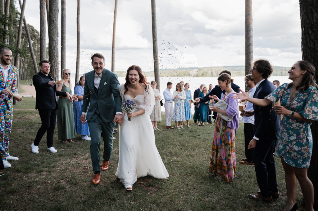 Glückliches Brautpaar geht durch ein Spalier nach freier Trauung am Brombachsee.
