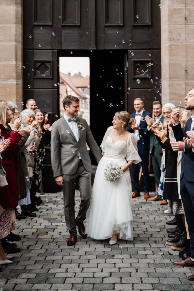 Brautpaar schreitet durch ein Spalier vor dem Fürther Rathaus nach standesamtlicher Trauung